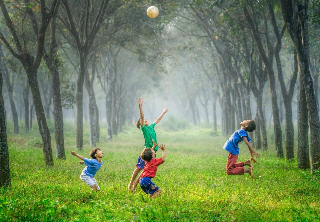 Barn leker med ball på gress