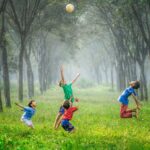 Barn leker med ball på gress