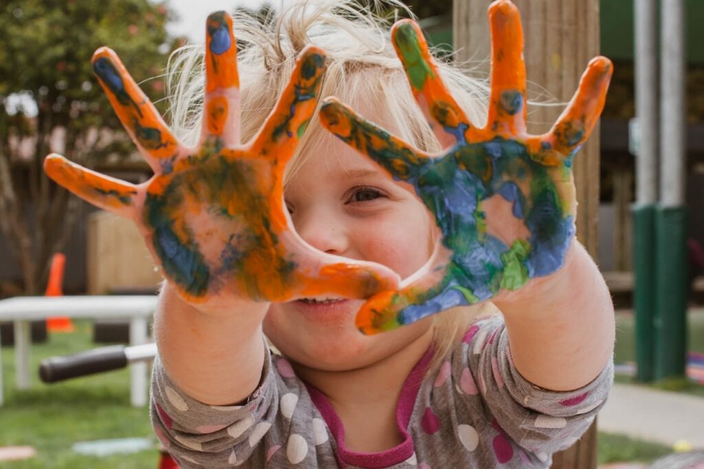 Smilende barn med hender dekket av maling
